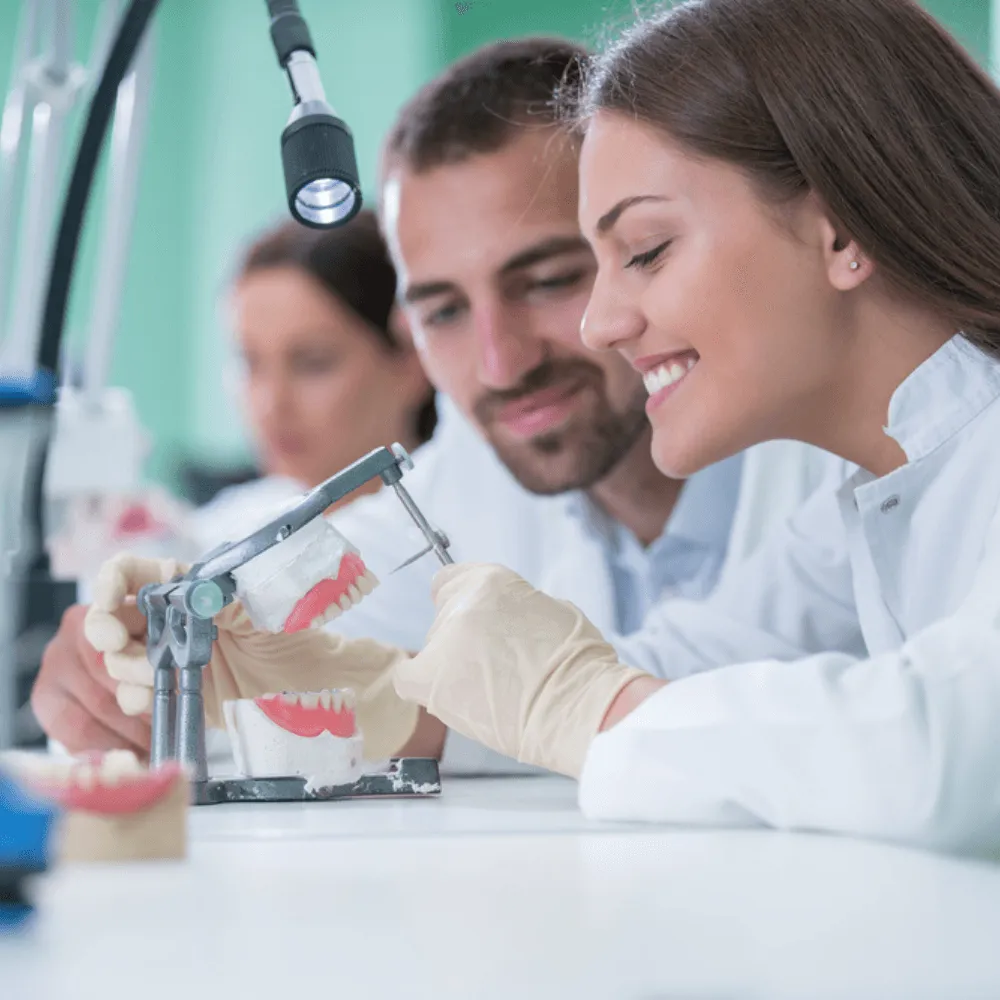 Two dental lab technicians crafting a custom night guard from a dental model