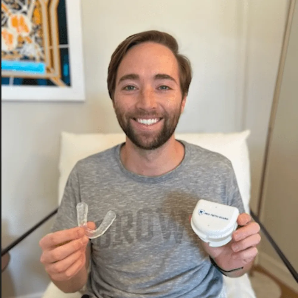 A happy customer holding his Pro Teeth Guard night guard and case at home